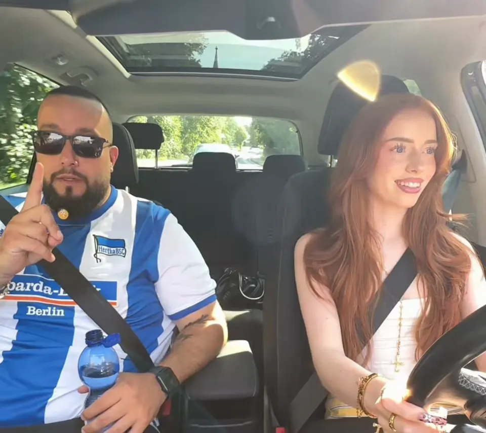Tolga erklärt mit erhobenem Finger eine Regel, die Fahrschülerin hört zu